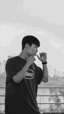 a black and white photo of a young man wearing a jbna t-shirt
