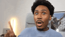 a man with a surprised look on his face is wearing a blue shirt