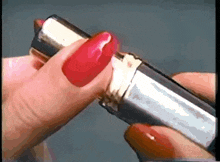 a woman with red nails is opening a lipstick tube