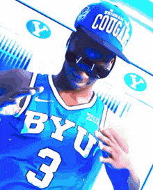 a man wearing a blue byu jersey and a blue cougars hat