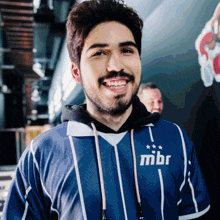 a man wearing a blue and white striped shirt with the word mbr on the front