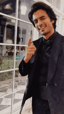 a man in a black suit is giving a thumbs up sign