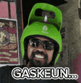 a man wearing sunglasses and a green helmet that says gaskeun on it