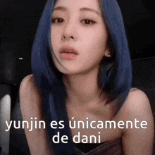 a woman with blue hair is wearing a strapless top and has the words yunjin es unicamente de dani written on her face .