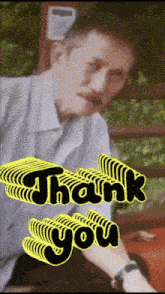 a man 's face is behind a yellow thank you sign