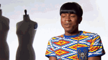 a man wearing a colorful shirt is standing in front of a mannequin with his eyes closed .