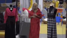 a woman in a red coat is standing in front of mannequins in a room with a sign that says giv on it