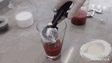 a blender is being used to mix a red liquid in a glass which says made in animotica on the bottom