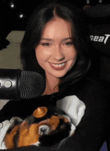 a woman holding a stuffed animal in front of a microphone with the word seat on her shirt