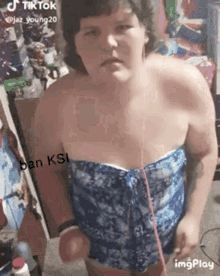 a woman in a blue strapless top is standing in a room with a caption that says ban ksi .