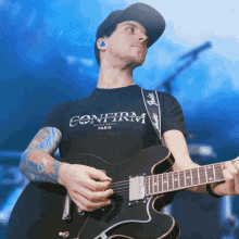 a man playing a guitar with a confirm paris shirt on