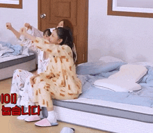 two girls in pajamas are sitting on a bed with the number 100 in red