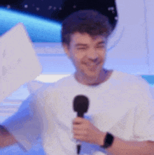a man in a white shirt is holding a sign and a microphone .