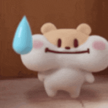 a stuffed animal with a smile on its face is holding a blue drop .