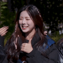 a young woman is smiling and giving a thumbs up while standing next to a group of people .