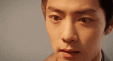 a close up of a young man 's face looking at the camera with a serious look on his face .