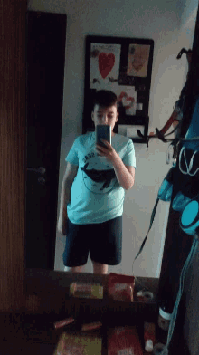 a man taking a picture of himself in a mirror with a t-shirt that has a whale on it