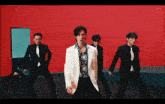 a group of men in suits and ties dancing in front of a red wall
