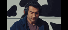 a man wearing headphones is looking down in front of a cow print wall