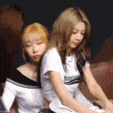 two young women are sitting next to each other on a couch .