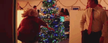 a man and a woman are decorating a christmas tree .