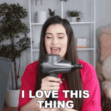 a woman in a pink shirt is holding a massage gun and says i love this thing