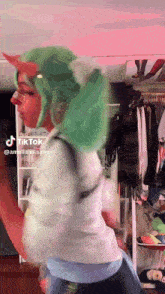 a woman with green hair is dancing in front of a rack of clothes and a sign that says tik tok