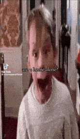 a young boy is standing in a hallway with his mouth open and says are u home alone