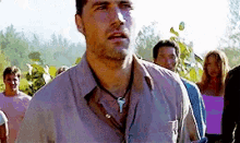 a man wearing a necklace stands in a crowd of people .