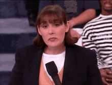a woman in a suit is holding a microphone in front of a crowd