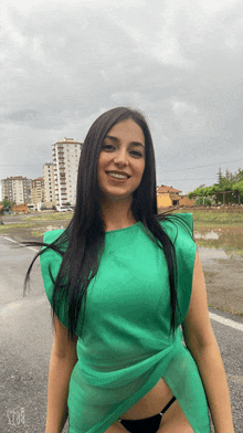 a woman wearing a green top and black underwear smiles