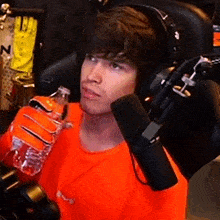 a man wearing headphones holds a bottle of water in front of a microphone