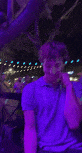 a man wearing a purple shirt is smiling in front of purple lights