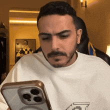 a man with a beard is holding a cell phone in his hand
