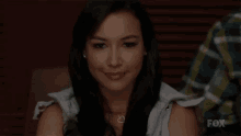 a woman is smiling at the camera while sitting at a table .