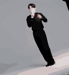 a man in a black suit is wearing a mask and making a peace sign