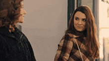 two women are standing next to each other and one of them is wearing a plaid coat