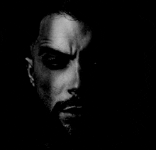 a close up of a man 's face in the dark with a beard .