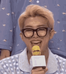 a man wearing glasses is smiling while holding a microphone in his hand .