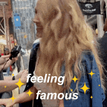 a woman in a denim jacket is being interviewed and the words feeling famous are visible
