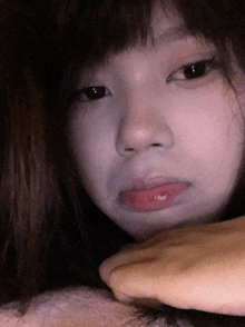 a close up of a woman 's face with a hand covering her mouth