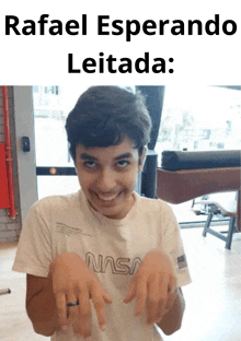 a young boy wearing a nasa shirt is making a funny face with his hands