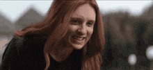 a woman with red hair is smiling for the camera .