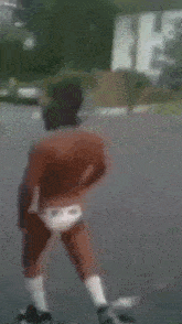 a man without a shirt is dancing on a street .