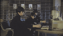 a man sits at a desk in front of a computer monitor and a map