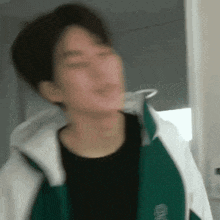 a blurry picture of a man wearing a green and white jacket .