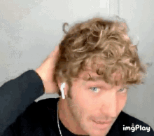 a man with curly hair is wearing ear buds .