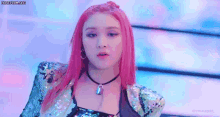 a woman with pink hair and a necklace is wearing a sequined jacket .