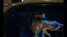 a man wearing sunglasses and a blue hoodie is sitting in the back seat of a car .