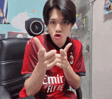 a man wearing a red emirates fly be shirt making a funny face